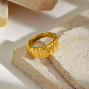 Macro shot of gold wide band ring with grooved texture on rustic stone background