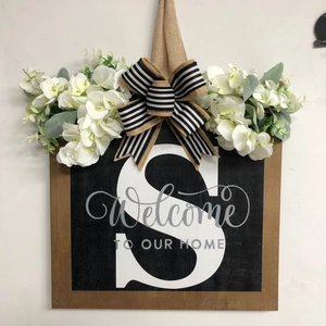 Detail of wooden welcome sign with letter S, hydrangea flowers and burlap bow decor