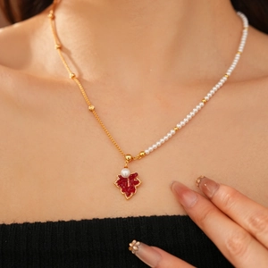 Gros plan d'un collier plaqué or 18 carats avec pendentif feuille d'érable rouge et perles