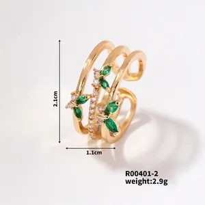 Detail view of triple-layered golden ring featuring green marquise gems and white zircon