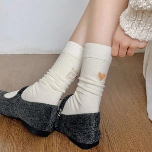 Detailed embroidery of heart and quote on cream cotton socks worn with Mary Jane shoes