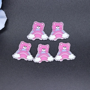 Close-up of five cartoon pink bear and rainbow DIY charms for crafts and phone cases