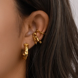 Detailed view of 18K gold plated rivet style hoop earrings and ear cuffs on a model