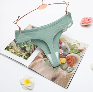 Close-up of bean green ribbed cotton thong with lace trim on a white decorative background