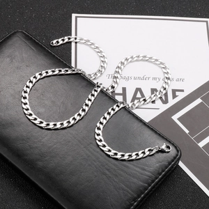 Detail of silver Cuban link chain with lobster clasp on black leather background