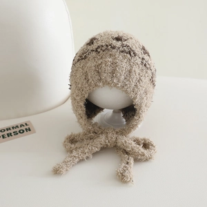 Detail of winter plush ear-flap hat featuring textured jacquard and long beige ties