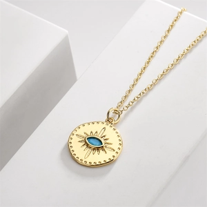 Detailed close-up of a golden eye pendant with blue zircon and radial engravings