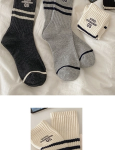 Detailed close-up of striped cotton socks with letter embroidery on white fabric