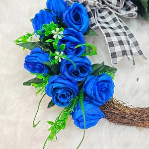 Detail of blue faux roses wreath with plaid bow on a soft white plush background