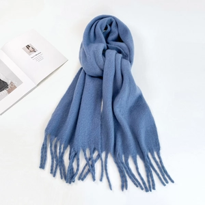 Close-up of thick light blue knit mohair scarf featuring classic long fringe tassels