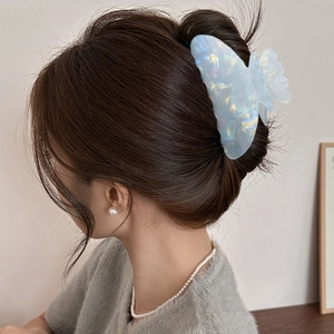 Pince à cheveux papillon bleu iridescent sur modèle pour coiffure arrière élégante