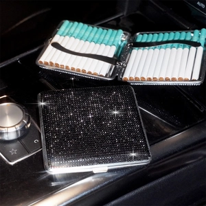 Detail of thin black stainless steel cigarette case with rhinestones on car console