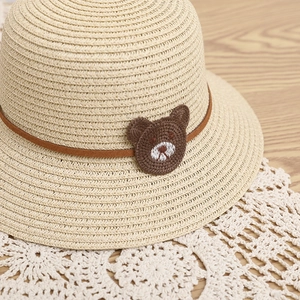 Kids beige straw sun hat featuring a cute brown crochet bear on a woven texture band