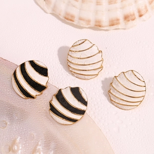 Macro shot of shell-shaped enamel earrings with nautical stripes and gold finish details