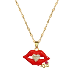Detail of gold necklace with red lip pendant, crystal heart, and a Kiss metal tag