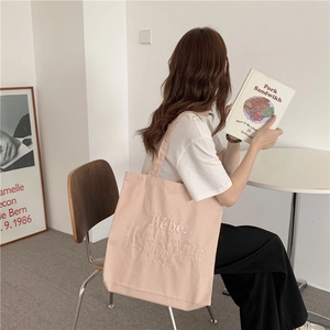 Detailaufnahme der rosa Canvas-Tragetasche mit besticktem Zitat und breitem Schultergurt