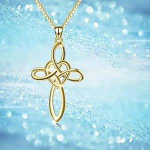 Close-up of golden cross necklace with heart knot pendant and fine chain detail
