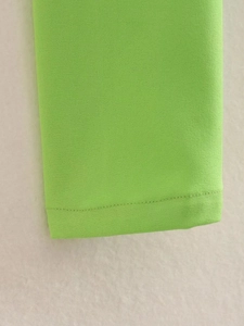 Detailed view of neon green fabric with high-quality single needle stitching and smooth hem