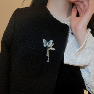 Detailed view of zircon butterfly brooch with tassel pendant on black tweed blazer