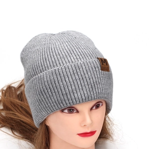 Detailed view of grey ribbed knit beanie with brown leather M FASHION label patch