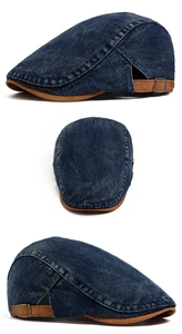 Detail of washed denim beret featuring brown contrast brim and adjustable bronze buckle