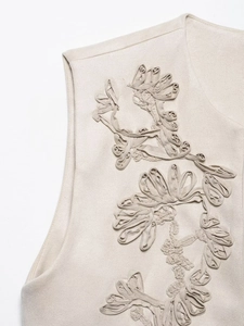 Detailed macro view of beige faux suede fabric with 3D floral embroidery applique texture