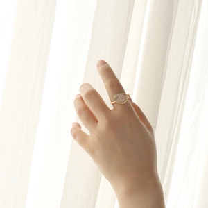 Minimalist 925 sterling silver ring with oval white crystal worn by a hand in natural light