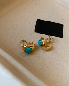 Detail of 18k gold plated C-shape earrings featuring turquoise stone inlays