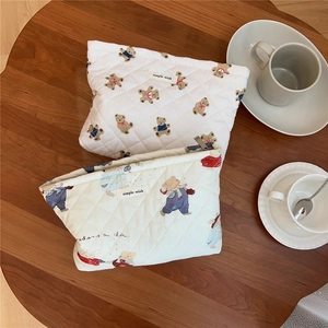 Detailed view of quilted cotton cosmetic bags with cute bear prints on a wooden table