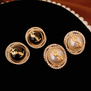 Luxurious gold YSL stud earrings with inlaid rhinestones and faux pearls on black velvet
