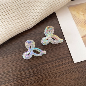 Close-up of holographic butterfly hair clips on a textured wooden surface