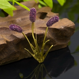 Detailed view of vintage gold lavender brooch with purple beaded clusters on wooden background