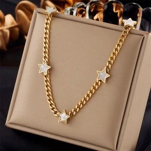 Elegante goldene Halskette mit fünf weißen Sternanhängern auf einer Schmuckschatulle
