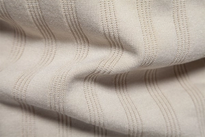 Makroaufnahme von beigem Strickstoff mit vertikaler Rippenstruktur und weicher Haptik