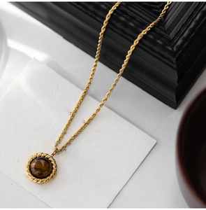 Detail of vintage tiger eye stone pendant with gold twisted rope chain for sweaters