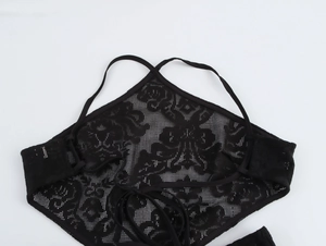 Close-up of black floral lace halter top with cross-back tie design on white background