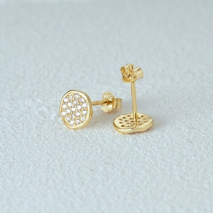 Detailed close-up of gold round stud earrings with shimmering white cubic zirconia stones