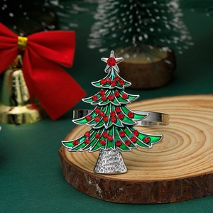 Detailed view of a silver napkin ring with a green enamel Christmas tree and red rhinestones