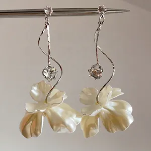 Gros plan sur boucles d'oreilles argentées avec pétales blancs et cristaux