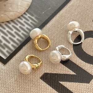 Minimalist S925 silver and gold pearl earring hoops set on textured fabric background