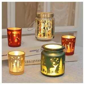 Detailed view of Christmas glass candle holders with deer and tree patterns and warm light