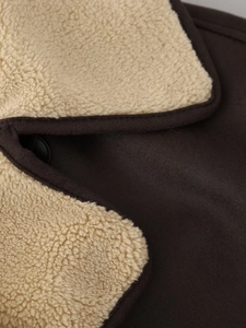 Detailed close-up of brown suede jacket collar with beige faux shearling lining