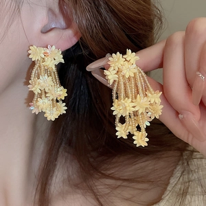 Close-up of yellow flower tassel earrings with intricate beadwork on female model
