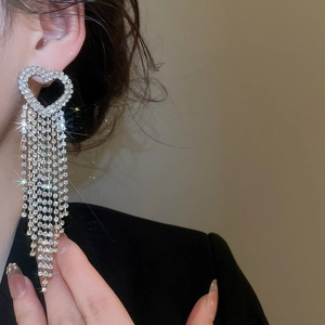 Detail of silver heart-shaped drop earrings with shimmering rhinestone fringe on a model