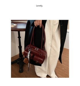 Detail of burgundy patent leather bag with silk scarf and pompom charm decoration
