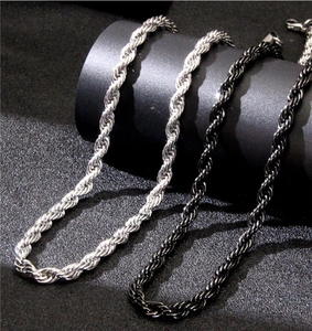Detail of twisted rope chains in silver and black stainless steel on a dark pedestal