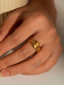 Macro detail of gold coffee bean link ring featuring a minimalist pig nose chain design