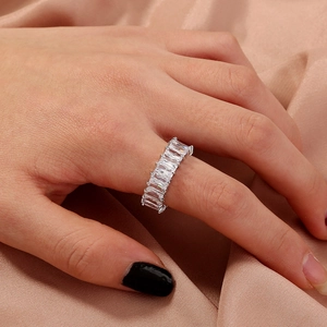 Macro detail of silver eternity ring with emerald cut white zircons on pink silk