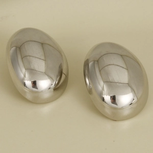 Macro shot of silver-colored teardrop earrings with smooth polished mirror finish
