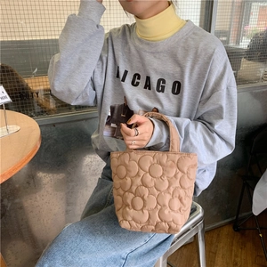 Quilted floral tote bag in khaki finish being carried by a model in casual wear